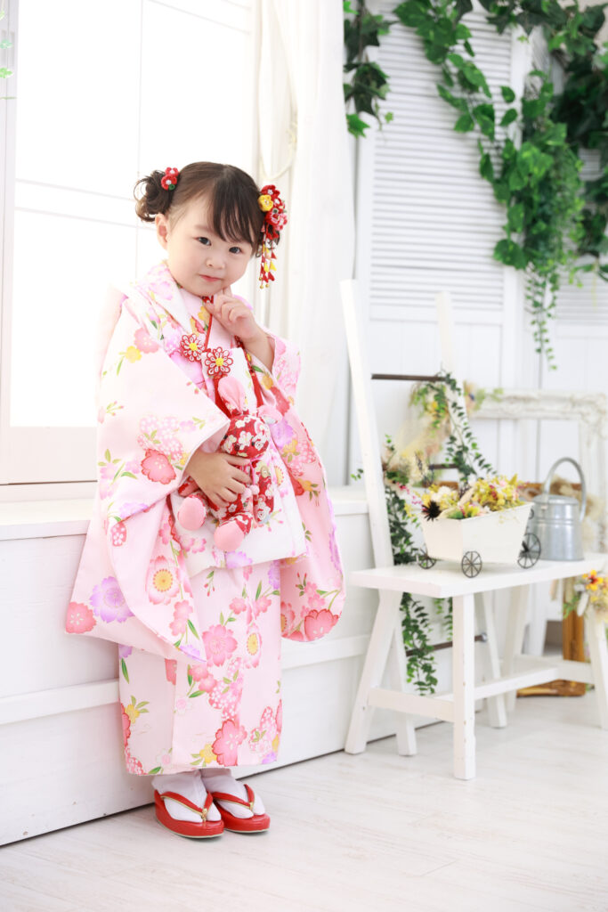 ピンクの着物と白被布でにっこり笑う3歳女の子の写真