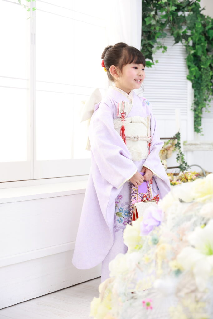 淡いラベンダー色の着物に白い帯で清楚な雰囲気の7歳女の子