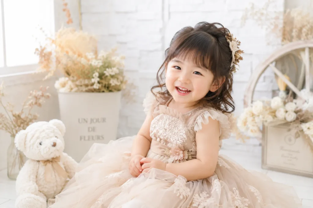 ベージュのドレスで笑顔になった七五三3歳女の子のスタジオ写真