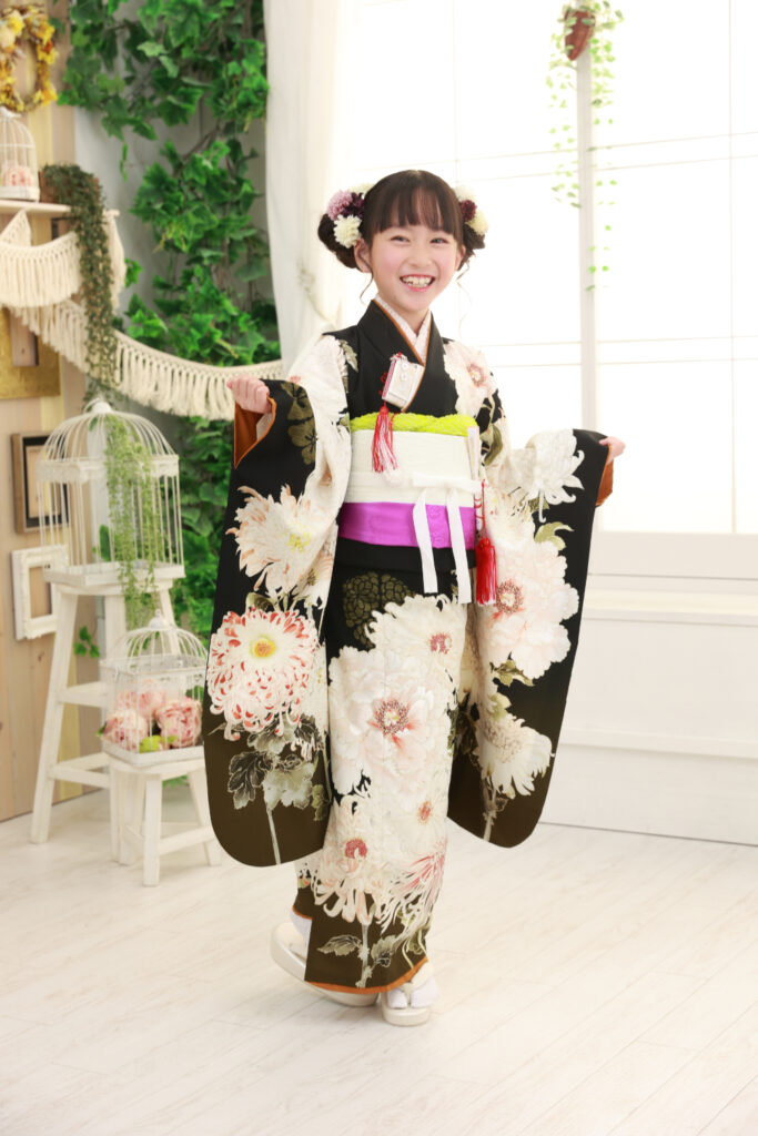 大きな花柄が映える黒の着物で笑顔の女の子