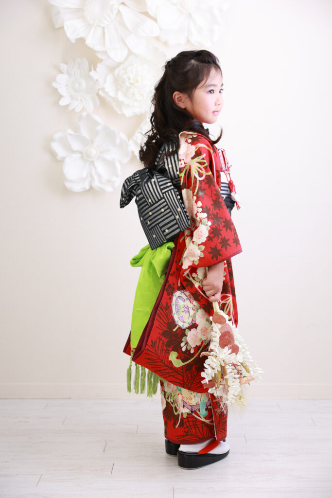 赤い着物を着て横顔を見せる7歳の女の子