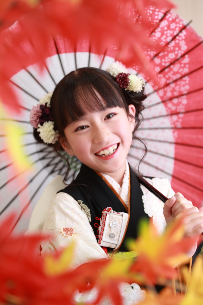 黒地の着物に和傘を合わせて笑顔を見せる7歳の女の子
