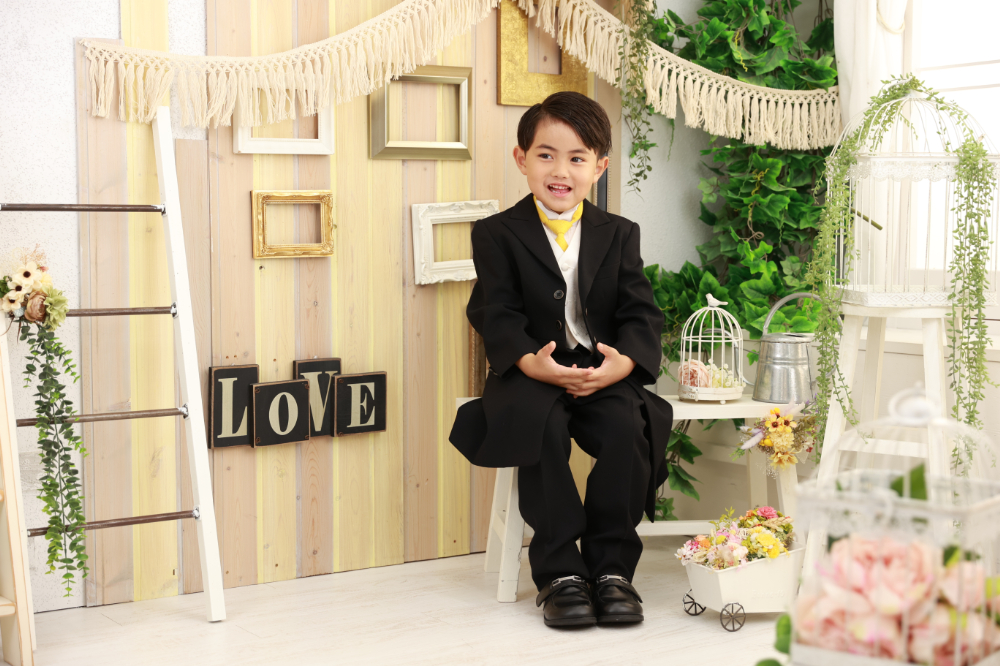 黒のスーツ姿で椅子に座る5歳男の子