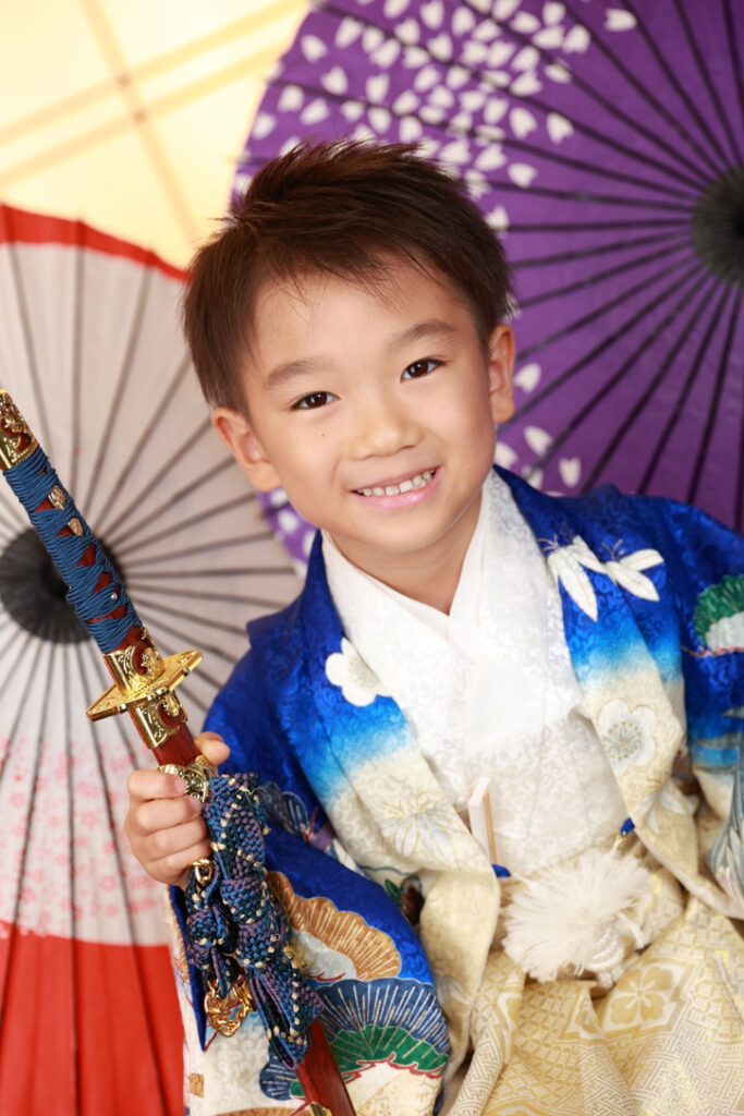 青の着物に刀を合わせたポーズをとる5歳男の子