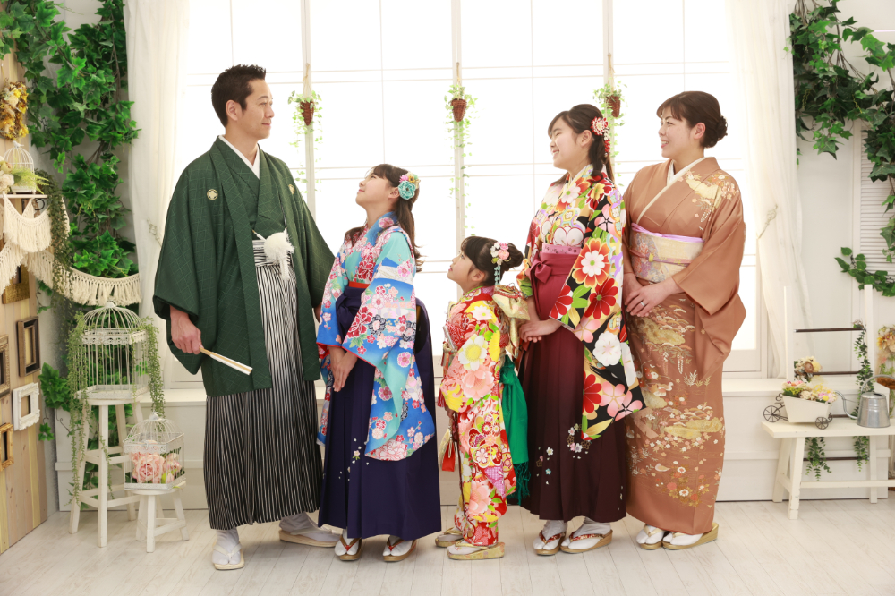和装で揃えた5人家族が向かい合って笑顔を交わす写真