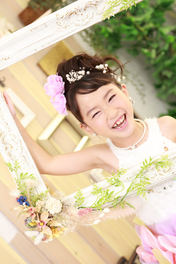額縁を持って笑顔を見せるおしゃれな7歳女の子
