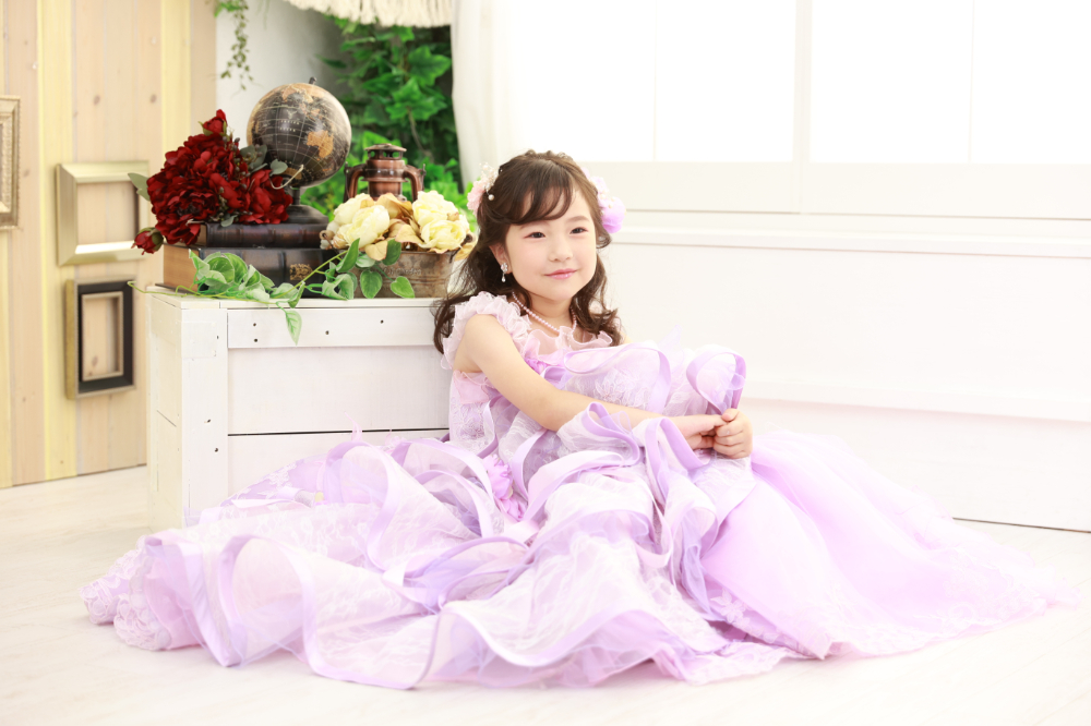 ラベンダーピンクのドレスを着た笑顔の7歳女の子