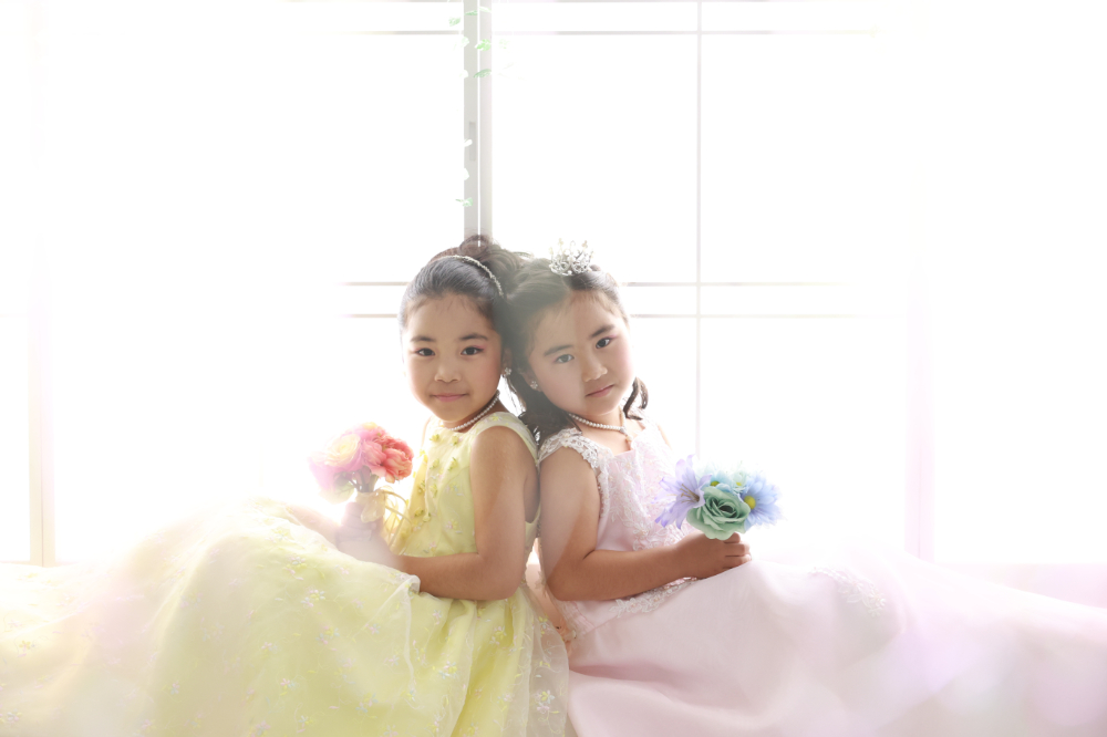 光あふれる空間でドレス姿の双子のような7歳女の子2人