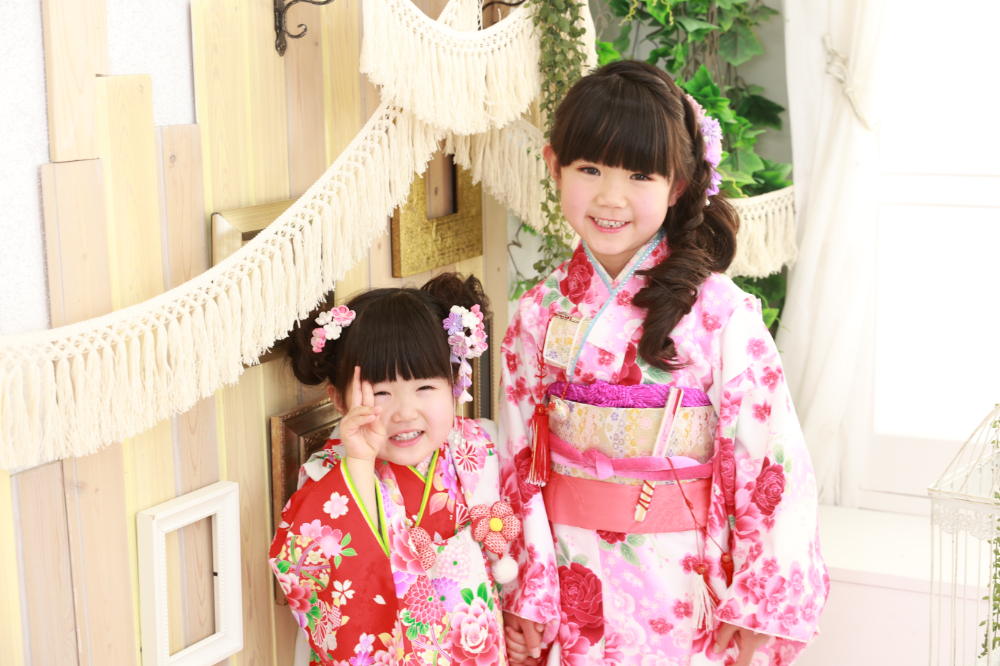 ピンク系の着物姿で仲良くポーズをとる姉妹