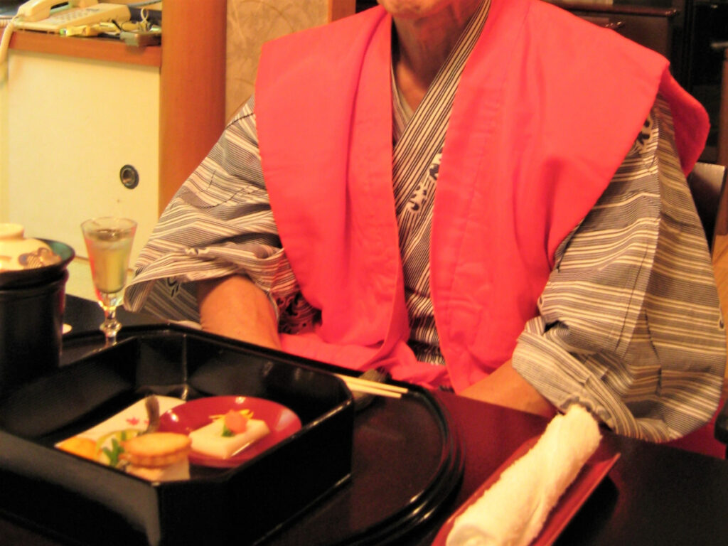 赤いちゃんちゃんこを着て還暦祝いをする写真