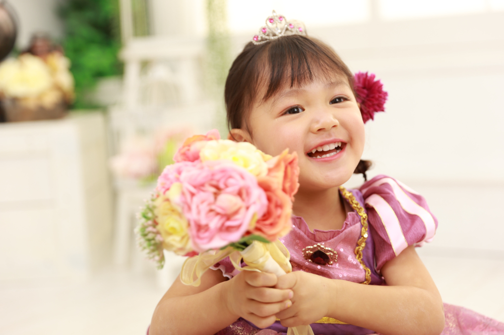 ストライプ調のパープルドレスで笑顔を見せる3歳の女の子