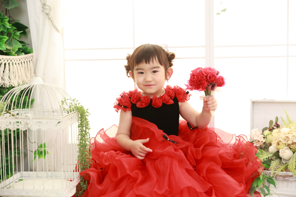 真っ赤なドレスで花束を持つ3歳の女の子