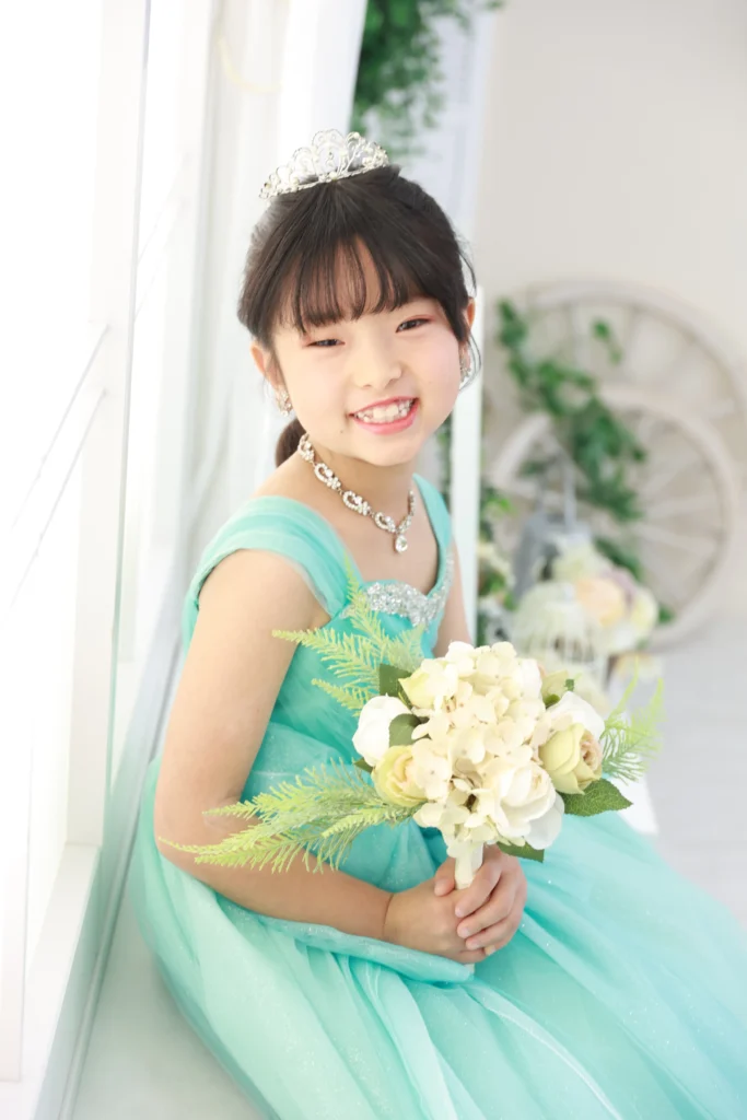７歳の女の子がミントグリーンのドレスで花束を持っている