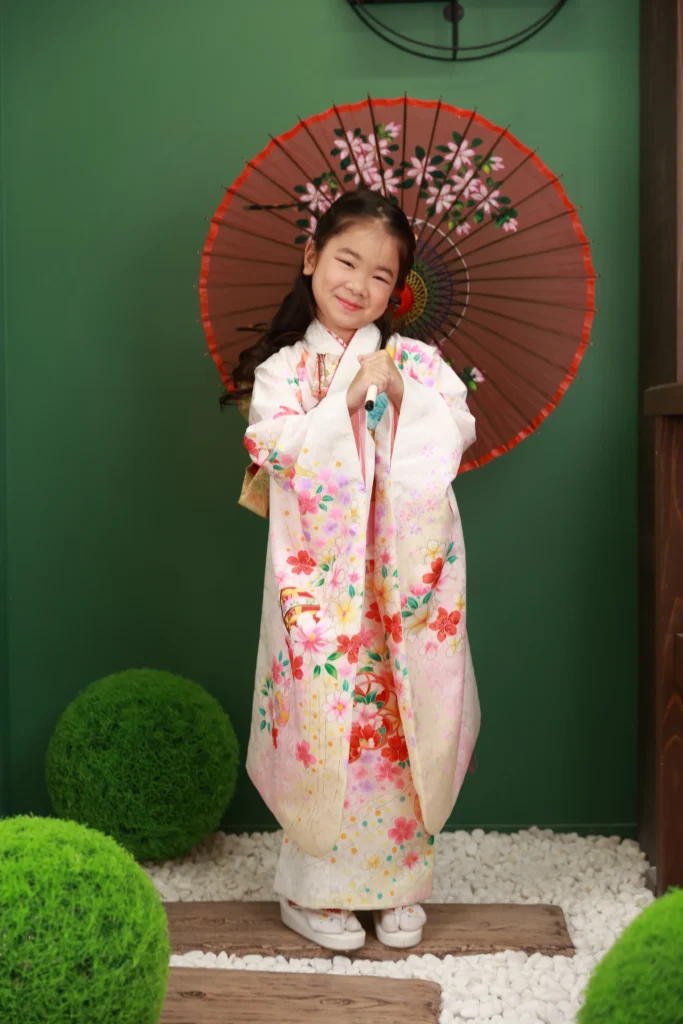 ７歳の女の子が和傘を持って七五三着物で立っている